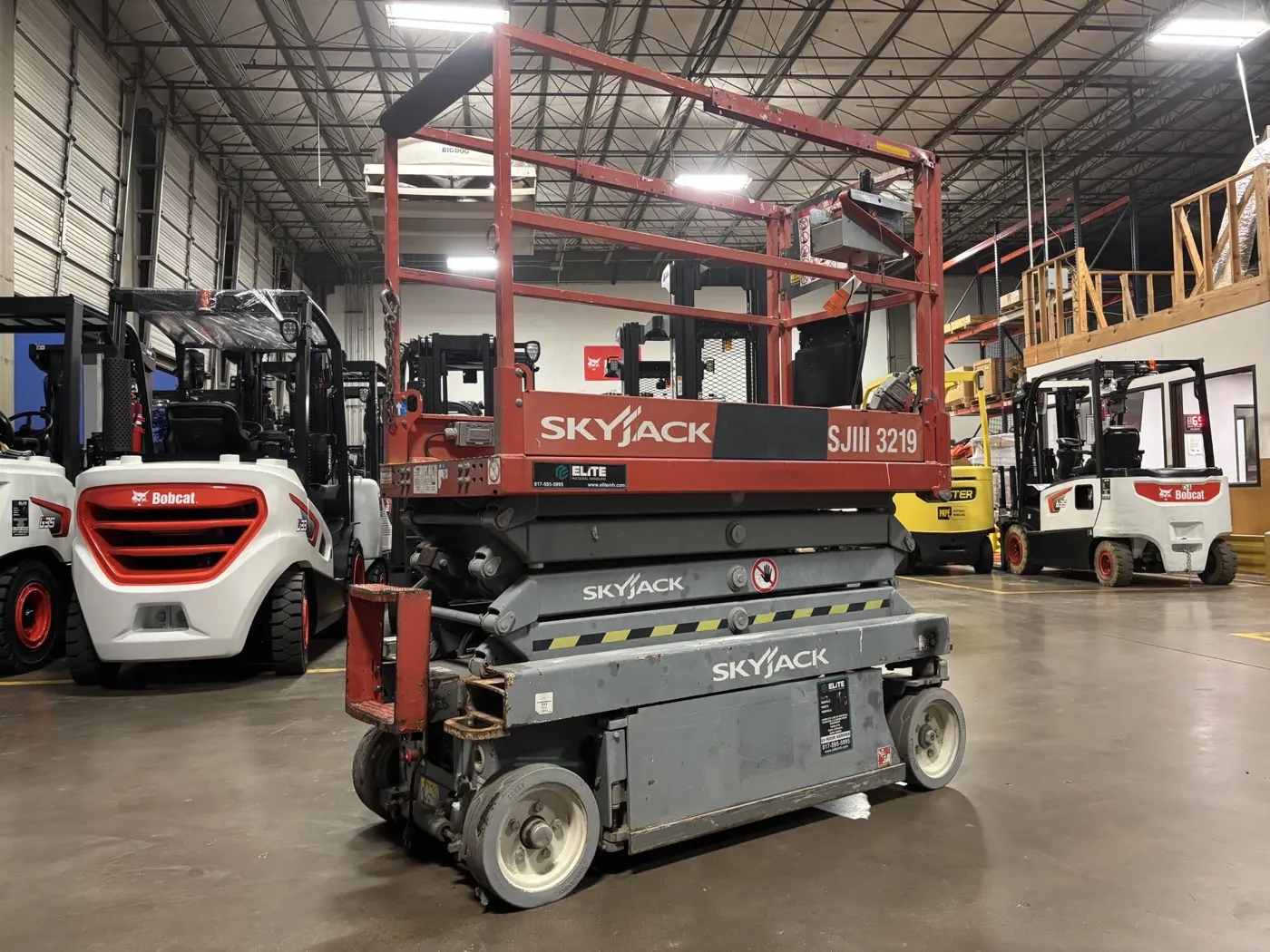 Scissor lift before refurbishment, with faded paint, scuffs and old stickers
