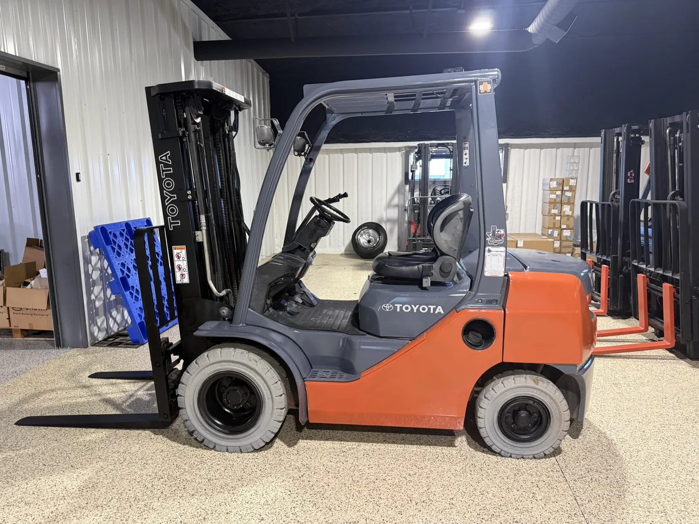 Same Toyota forklift after refurbishment, with fresh paint, black forks and new tires